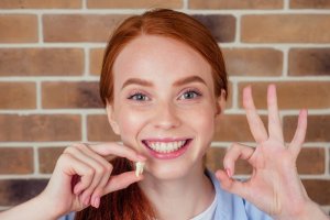 A woman proudly showing her removed tooth